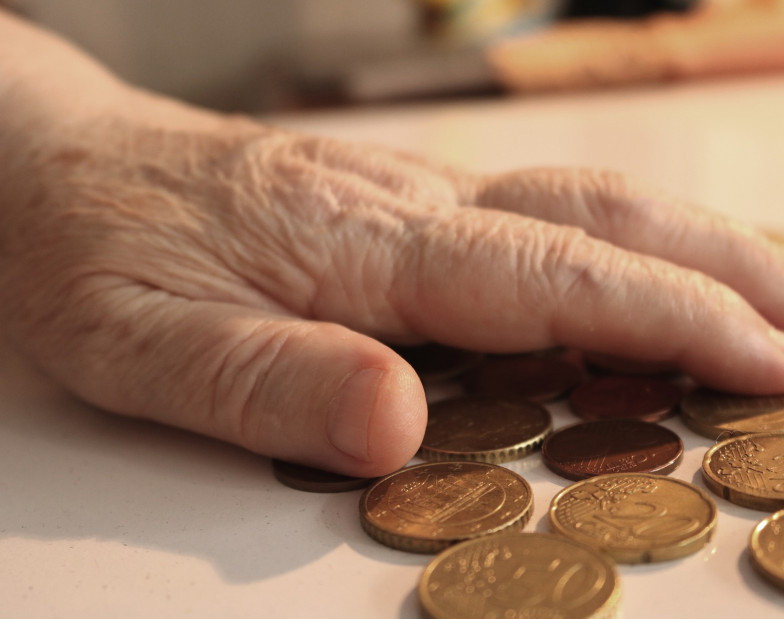 Foto: Hand einer Senioren, Geldmünzen liegen auf einem Tisch