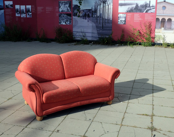 foto: eine rote Couch auf einer freien Fläche in der Stadt