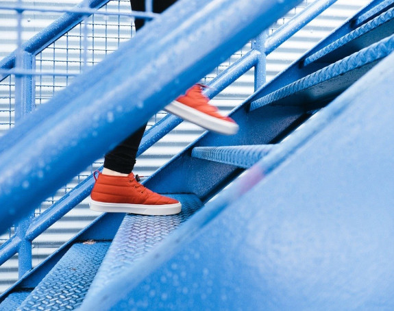 Foto: zwei Füße in roten Turnschuhen gehen eine Treppe hinauf