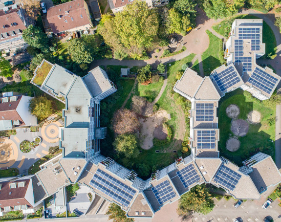 Draufsicht, Wohngebäude mit Solaranlage auf dem Dach, umgeben von Bäumen und weiteren Häusern