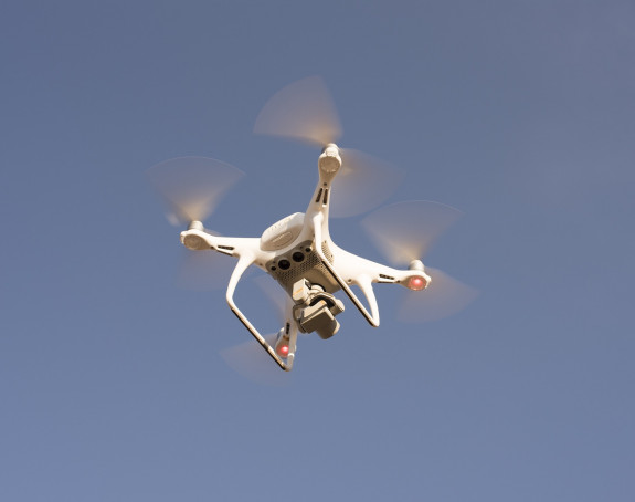 fliegende Drohne von unten vor blauem Himmel