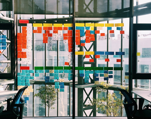 viele bunte Post-It-Notizen an einem Glasfenster in einem Büro