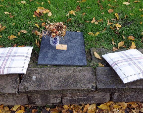 Foto: 2 Sitzkissen und eine Vase mit Blumen in einer Grünanlage