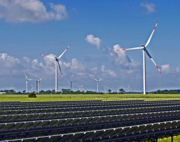 Freies Feld mit Windrädern und Solaranlagen bei Sonnenschein