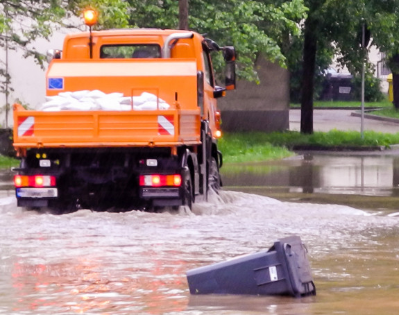Foto: Überflutete Straße in der Stadt, Mülltonne liegt im Wasser